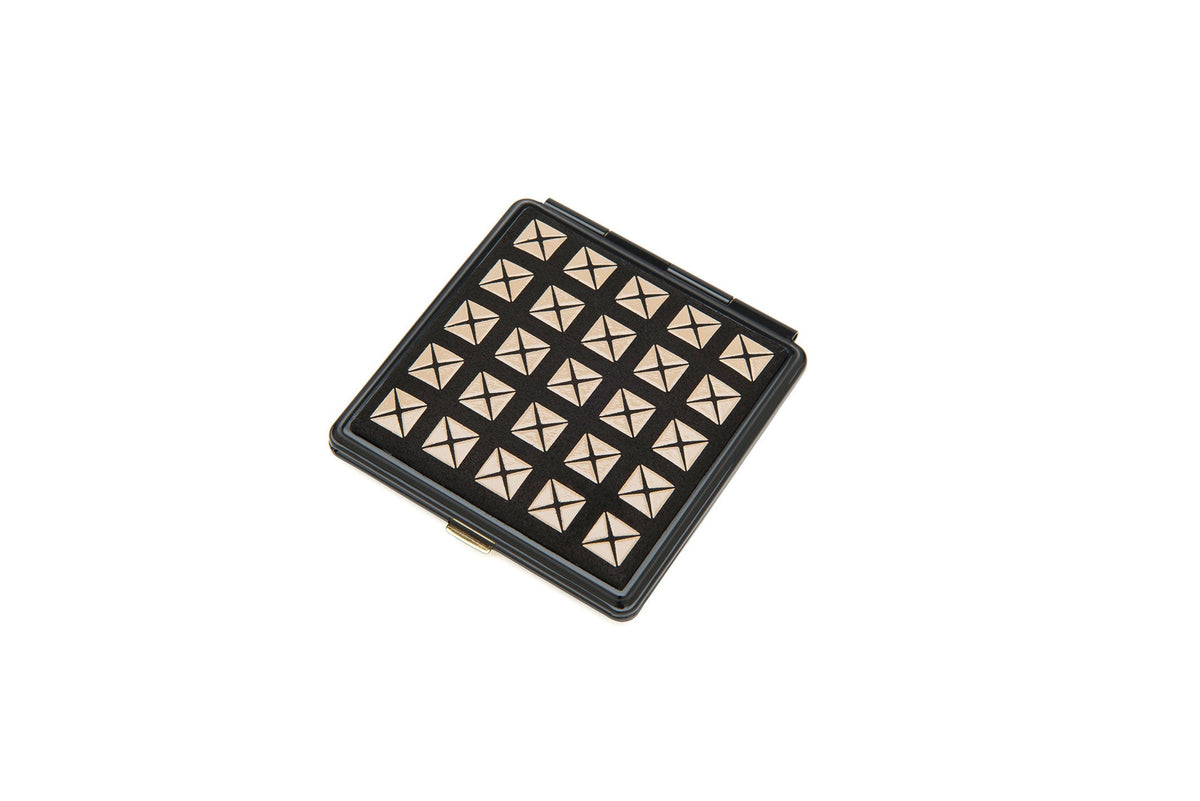Square compact mirror with a black frame featuring a grid of metallic pyramid studs on the top surface, shown against a white background.