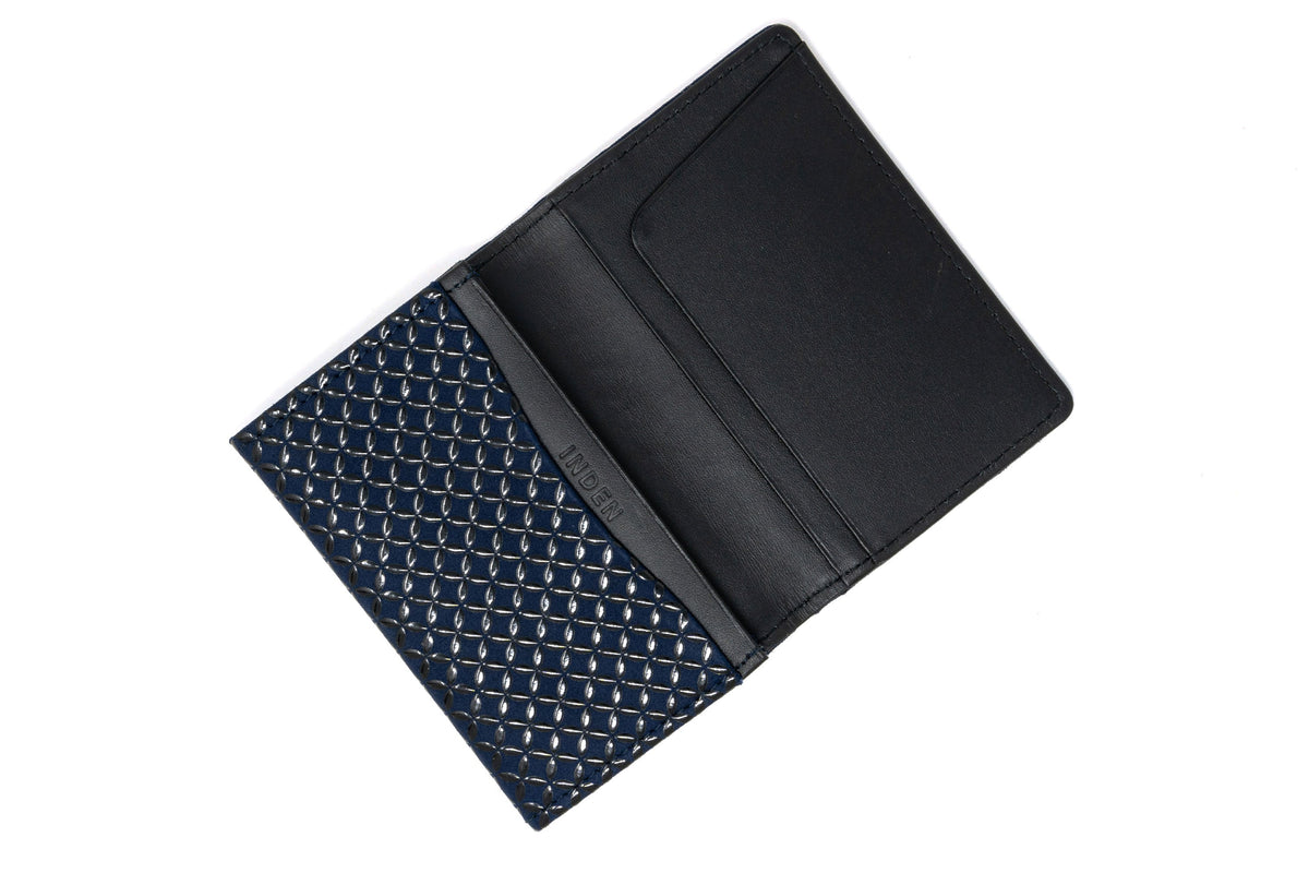 Open black leather business card case with an inner card slot featuring a detailed blue patterned fabric with silver accents on the left side.