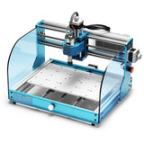 Compact desktop CNC router with blue frame, transparent protective side panels, and a flat perforated work surface beneath the spindle head controlled by lead screws.