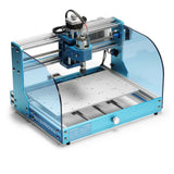 Compact blue desktop CNC router with transparent side shields, a metal work surface, and mounted spindle motor with wiring on top framework.