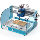 Blue and silver 3018-PROVer V2 desktop CNC router with transparent safety covers carving intricate patterns on a wooden plank on its metal bed