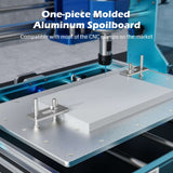 Close-up of a one-piece molded aluminum spoilboard secured by clamps on a blue CNC router bench with a cutting tool positioned above the board.