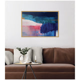 Abstract framed canvas wall art above a brown sofa, featuring bold horizontal brushstrokes in blue, teal, pink, and dark indigo with dripping paint effects.