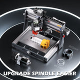 Compact desktop CNC router with aluminum frame and upgraded spindle in yellow and silver, shown with two additional spindle components and circular labeled areas on black surface.