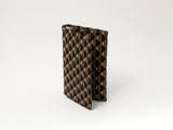 Small standing business card case with a black and beige diamond check pattern, shown upright on a plain white background.