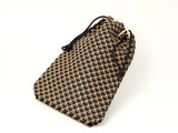 Drawstring pouch with black and beige geometric triangle pattern and black cords, shown on a white background.