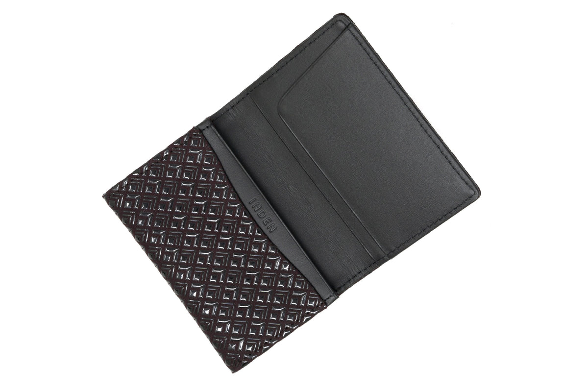 Open business card case featuring a black leather interior and a dark patterned exterior with a diamond geometric design.