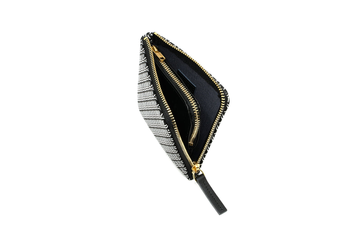 Black and white patterned zippered coin purse with gold-tone zipper and black pull tab, shown open to reveal a dark interior compartment.