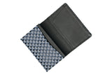Open business card case with a black interior and a navy blue exterior patterned with white chevron-like shapes, shown from above on a white background.