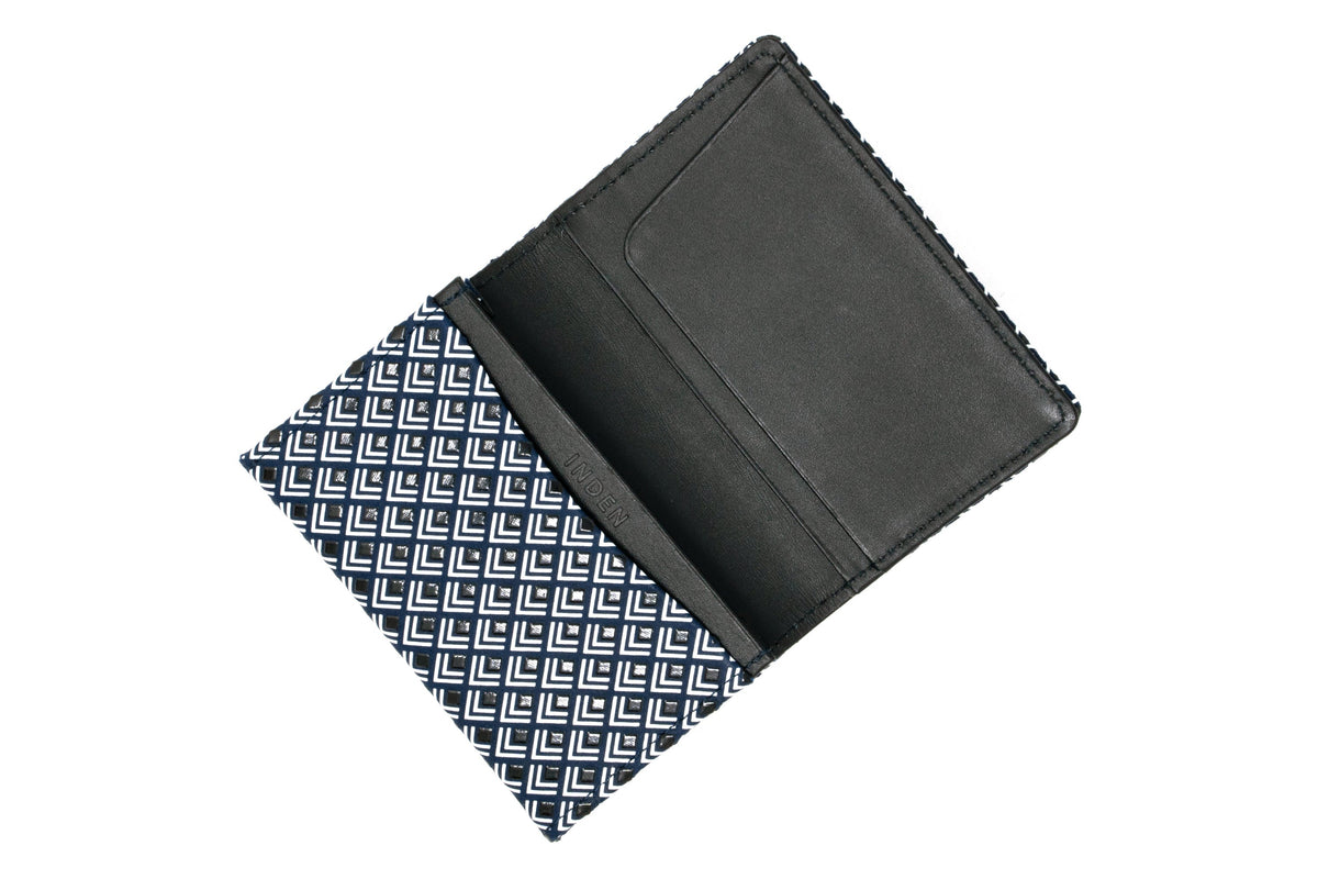 Open business card case with a black interior and a navy blue exterior patterned with white chevron-like shapes, shown from above on a white background.