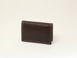 Compact dark brown leather business card case with a subtle embossed houndstooth pattern on the front panel, standing upright on a light beige background.