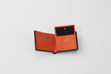 Partially opened bifold wallet with black exterior and vibrant orange interior featuring card slots and a snap-button coin pouch.