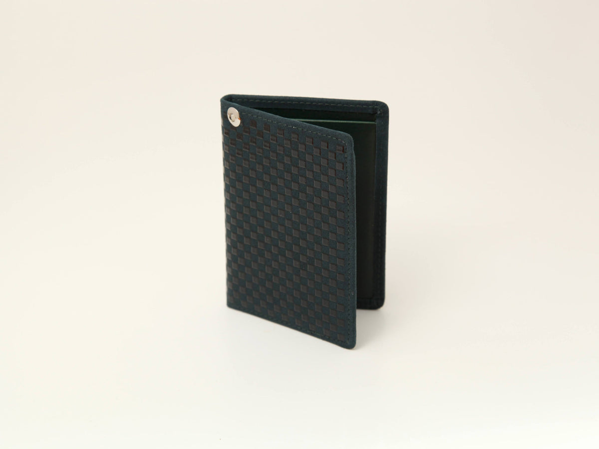 Dark green rectangular pass case with a textured checkerboard pattern on the front and a small metal emblem near the top corner, standing open against a plain background.