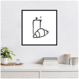 Minimalist black ink drawing of a steaming coffee pot and croissant on white canvas, framed and hanging on a white wall above a white desk.
