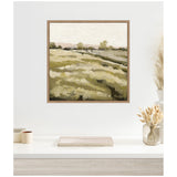 Framed canvas wall art depicting a muted green and beige field with trees along the horizon under a pale sky, hanging above a neutral-toned shelf with decor.