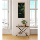 Tall framed canvas with aerial view of a winding, dark blue river running through a mossy green valley, displayed on white paneled wall between two windows.