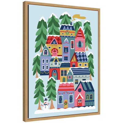 Sylvie Framed Canvas art showing a whimsical winter village scene with colorful houses, snow, evergreen trees, and a snowman.