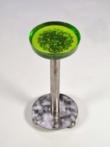 Martini table with a round, translucent green resin top featuring an embedded abstract pattern, supported by a slim metal pedestal and circular base with a brushed finish.