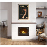 Black-framed prosecco poster with an illustrated ostrich wearing glasses and sipping prosecco above a lit fireplace in a cozy modern room with wooden floors and shelves.