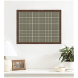 Rectangular wall-mounted fabric pinboard with sage green and cream plaid pattern framed in dark wood, hanging above a white surface with lamp, photo frame, and potted plant.