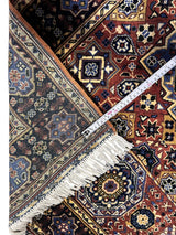 Close-up of hand-knotted Afghani Mamluk wool rug with intricate blue, brown, and cream geometric floral patterns and white fringe with taped measurement across.