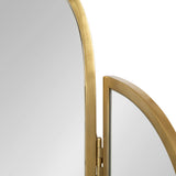 Close-up of a gold metal-framed tri-fold mirror showing the hinge connecting a smaller curved panel to a larger rectangular panel with rounded edges.