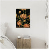 Framed canvas art with large peach and orange flowers and dark green leaves on a black background, hung above a rustic wooden nightstand holding a white cup and two books.