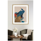 Printed artwork of a blue and gold peacock with detailed feathers perched among red peonies on a neutral linen background, framed above a lounge area with green armchairs and a wooden table.