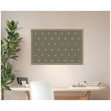 Rectangular pinboard with a muted green fabric featuring a subtle beige botanical block print pattern, framed in light wood, mounted above a minimalist wooden desk with white chair and plant.