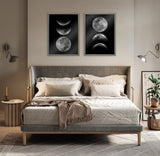 Two framed prints above a gray upholstered bed, each showing three phases of the moon against a black background, with neutral bedding and minimal bedroom decor.