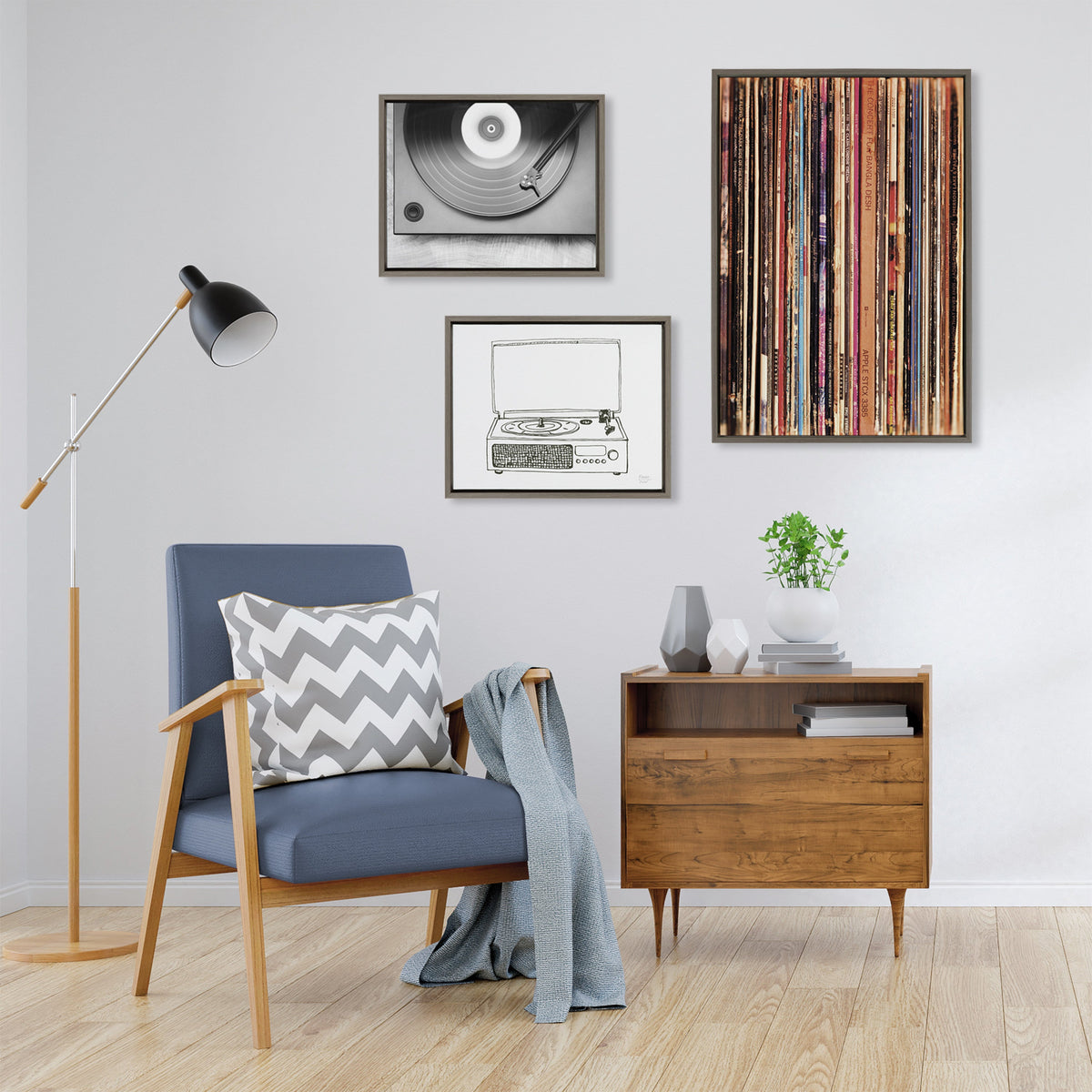 Contemporary living room corner with a blue armchair featuring wooden arms and a chevron pillow, next to a mid-century modern wooden sideboard under framed record-themed artwork.