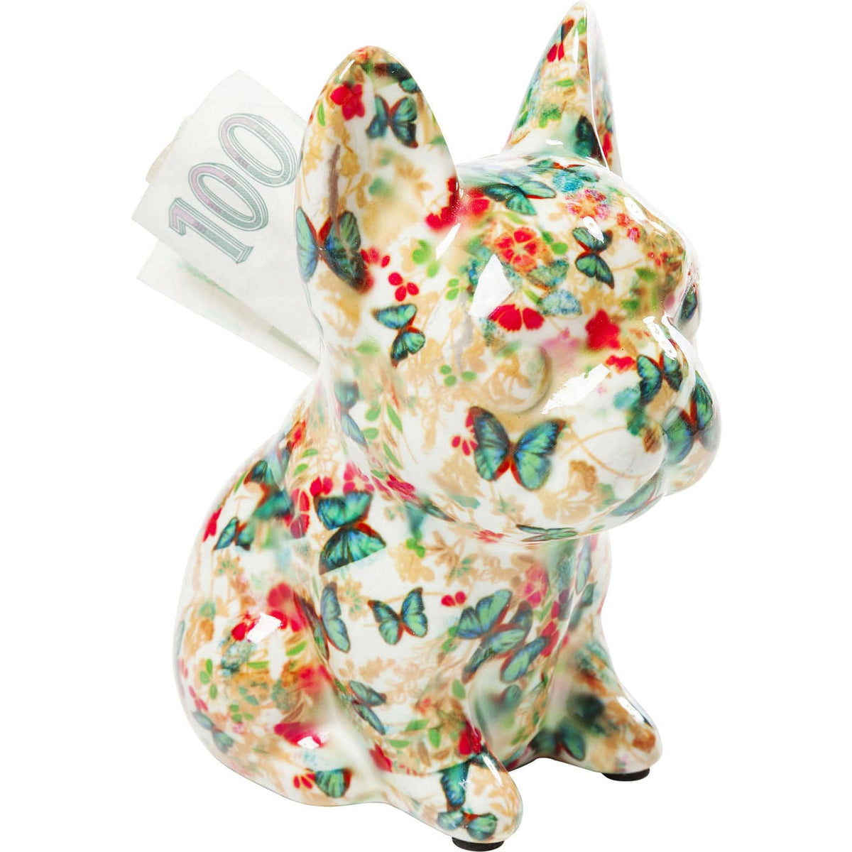 Small ceramic dog-shaped money box decorated with colorful butterfly and red floral patterns, with a 100 currency note inserted in the slot on its back.