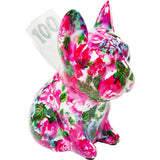 Small dog-shaped money box covered in vibrant pink, green, and purple floral patterns with a 100 currency note inserted at the back.