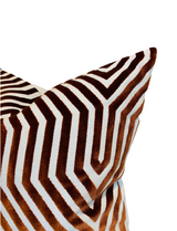 Close-up of a pillow with a russet and white geometric chevron pattern featuring velvet texture and sharp angled lines.