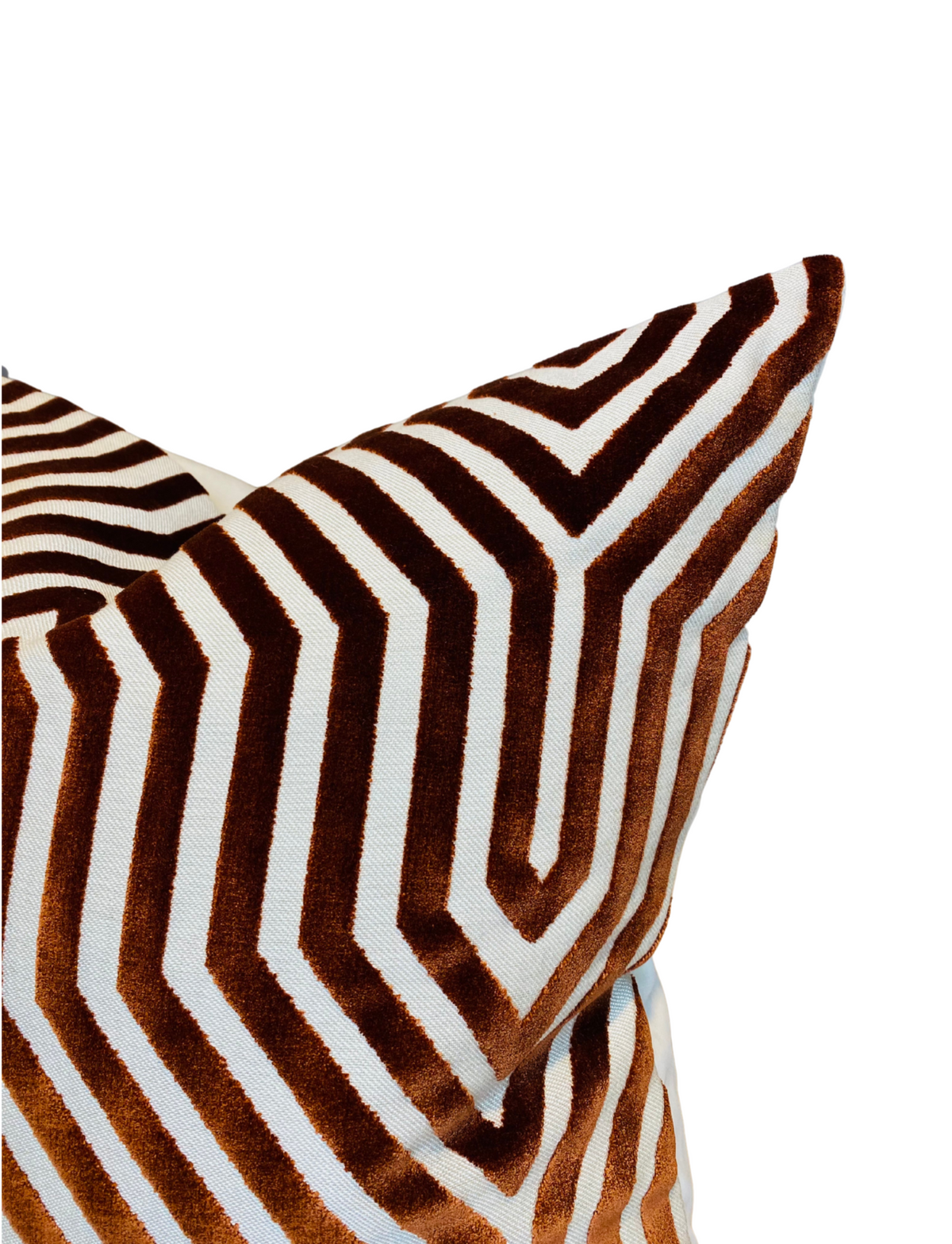 Close-up of a pillow with a russet and white geometric chevron pattern featuring velvet texture and sharp angled lines.
