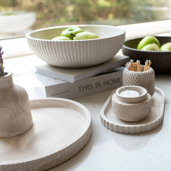 Decorative items including bowls, candles, and books on a table with a window in the background.