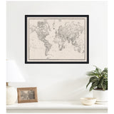 Framed vintage-style black and white world map with intricate detailing, hanging on a white wall above a shelf with a lamp, photo frame, and potted plant.