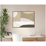 Abstract wall art in shades of beige, cream, and brown with layered organic shapes, framed in dark wood, hanging above a light-colored wooden desk with a white chair and green plant nearby.