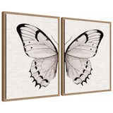 Two framed canvases each featuring one half of a black-and-white butterfly wing with delicate patterns on a neutral linen background, displayed side by side.