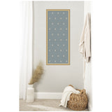 Rectangular blue pinboard with a repeating pattern of small white botanical block print flowers, framed in light wood, hanging on a light gray wall above a basket and vase.