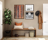 Entryway with framed record player-themed art including colorful vertical record spines, black and white sketch, and close-up vinyl image on taupe wall above wood bench.