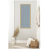 Tall rectangular pinboard with light blue plaid fabric framed in light wood, hanging on a white wall above a woven basket and decorative vase with pampas grass.