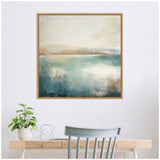 Abstract framed canvas featuring a calming lake landscape with soft blues, beige, and white tones, hanging on a white wall above a wooden desk with a chair, plant, and metal decor.