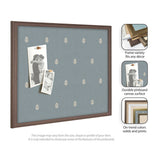 Rectangular pinboard with blue fabric featuring a small repeating white botanical pattern and a dark wooden frame, displaying two monochrome photo prints secured by clips.