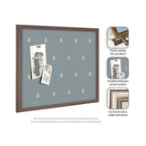 Rectangular pinboard with blue canvas featuring a repeating small white botanical leaf print, enclosed in a medium brown wooden frame, holding two black-and-white photos pinned with amber tacks.
