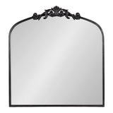 Rectangular mirror with a gently arched top and an ornate black decorative crest with scroll details on the upper edge.