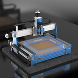 Compact CNC router machine with blue and silver frame, showing a 400x300 mm work area marked in translucent blue on its flat brown bed, set on a dark surface.