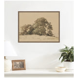 Sepia-toned framed canvas print of a cluster of leafy trees with soft shading, displayed on a white wall above a shelf with a lamp, photo frame, and potted plant.