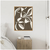 Abstract framed canvas with brown and off-white shapes resembling stylized leaves or petals on a light gray wall above rustic wooden bedside table with books and cup.