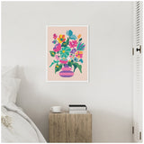 Framed abstract floral canvas in bright pink, teal, yellow, and green in a striped pink vase hanging on a white wall above a wooden nightstand with books and a teacup.